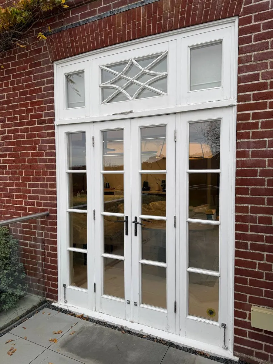 White timber french doors with decorative fanlight and glazed sidelights in red brick